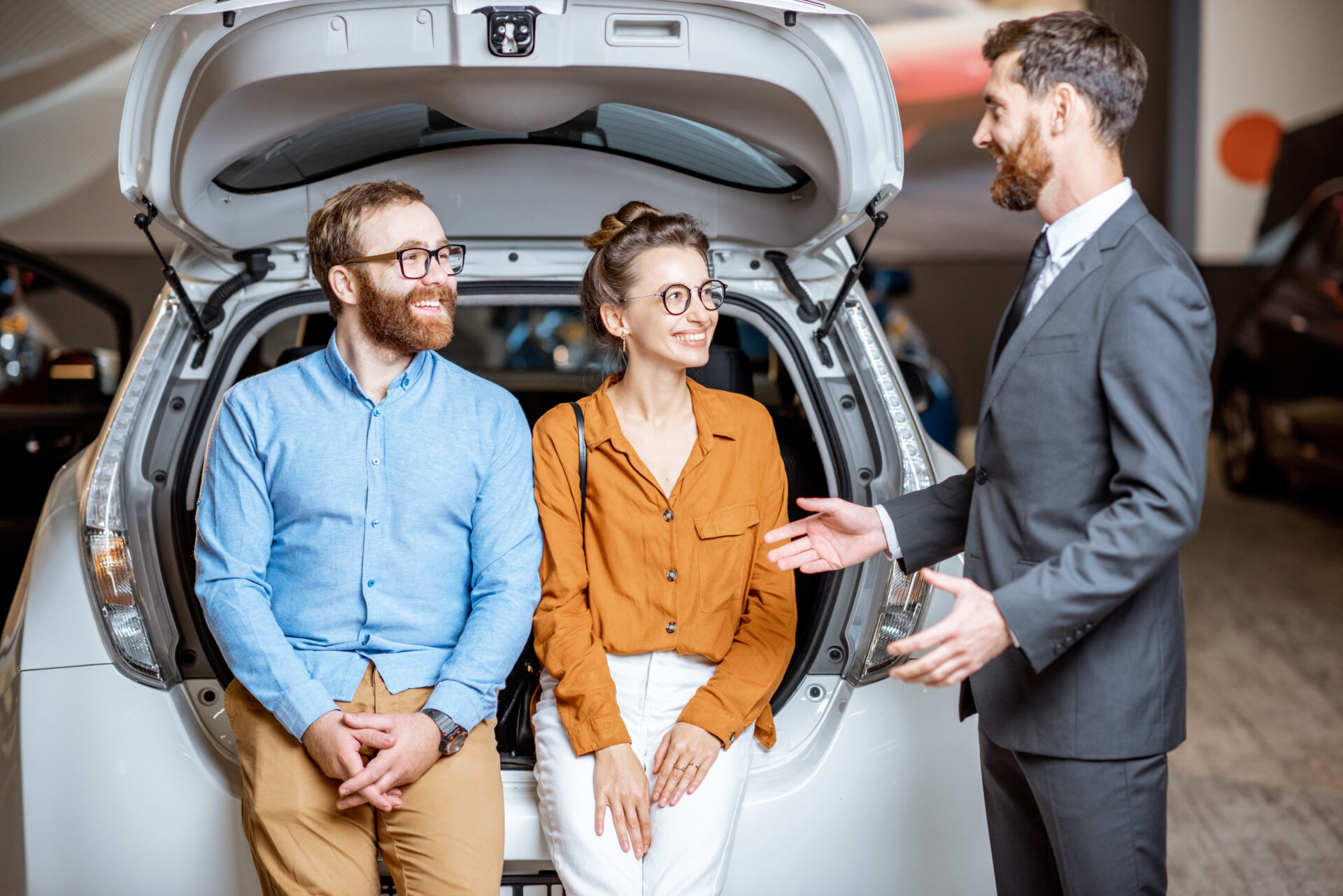 Couple with sales manager near the car in the showroom | Warrantywise