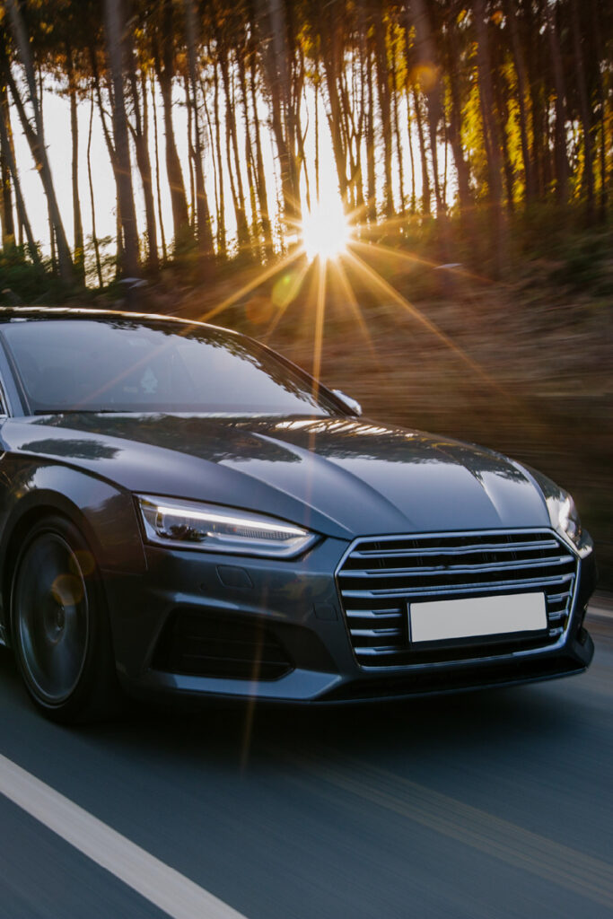 Car driving down the road with forest and sunset in the background