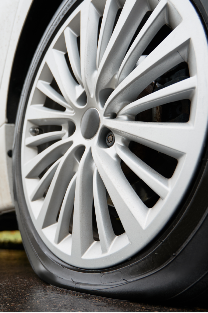 Close up of rear wheel with flat tyre on car