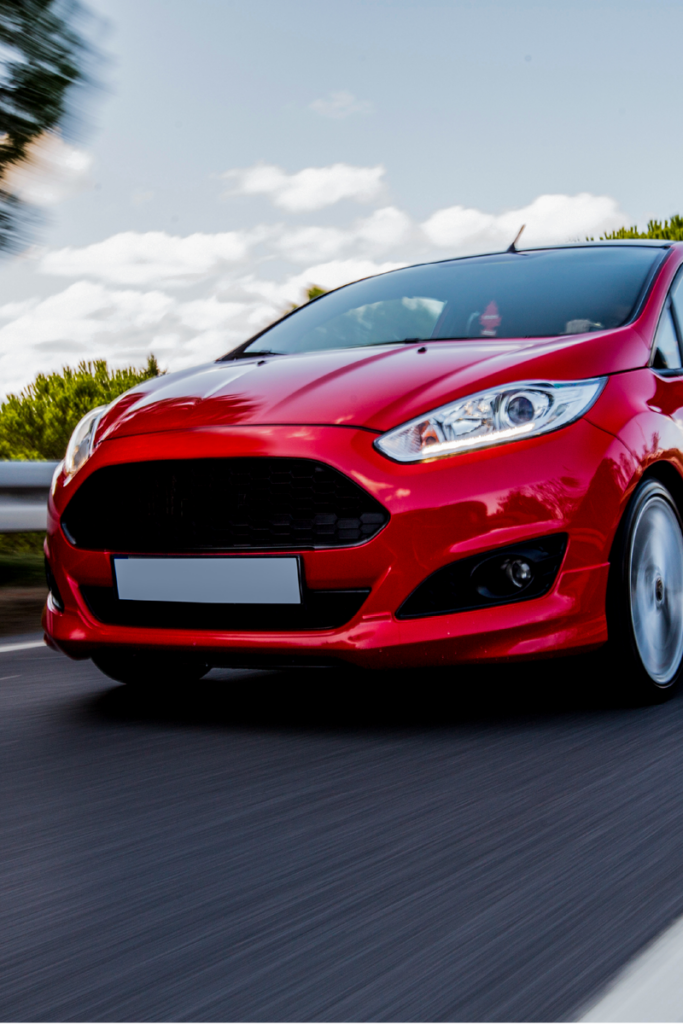 Red ford fiesta driving down a road