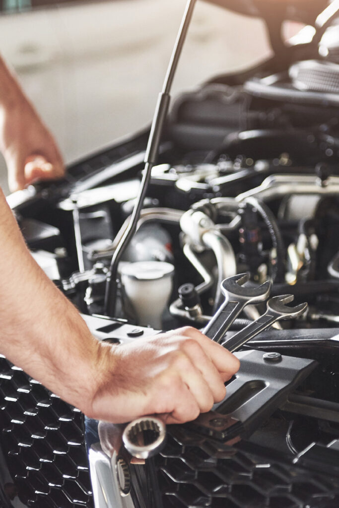 Car mechanic looking under the bonnet of the car.
