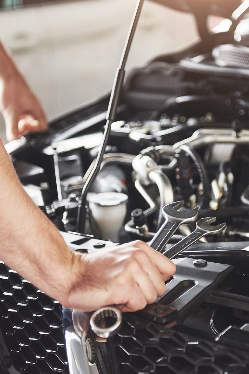 Car mechanic looking under the bonnet of the car.