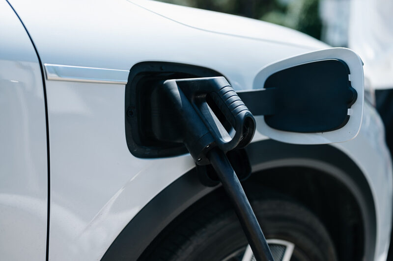 Hand plugging in a charger in an electric car socket.Electric ca | Warrantywise charger in an electric car socket