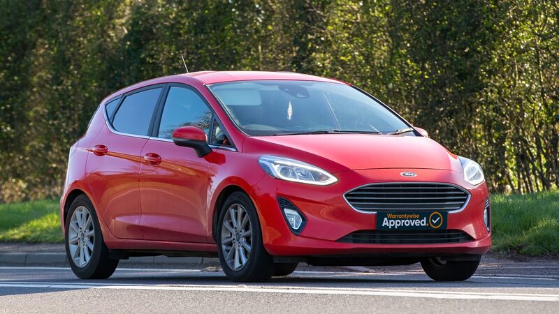 Red ford fiesta driving down a road