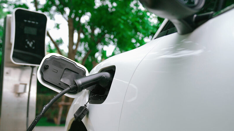 Closeup progressive concept of electric car being charged at charging station. | Warrantywise electric car being charged at plug-in charging station
