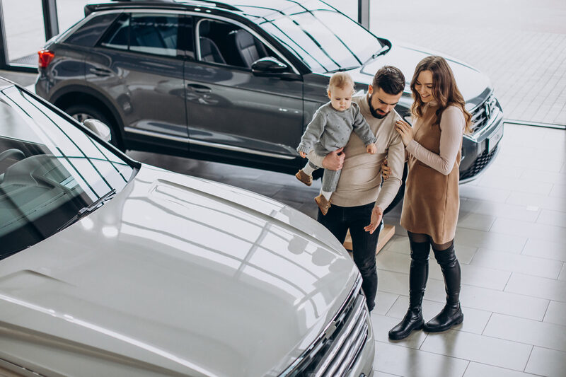 Family with toddler girl choosing a car in a car showroom | Warrantywise Family with toddler girl choosing a car in a car showroom