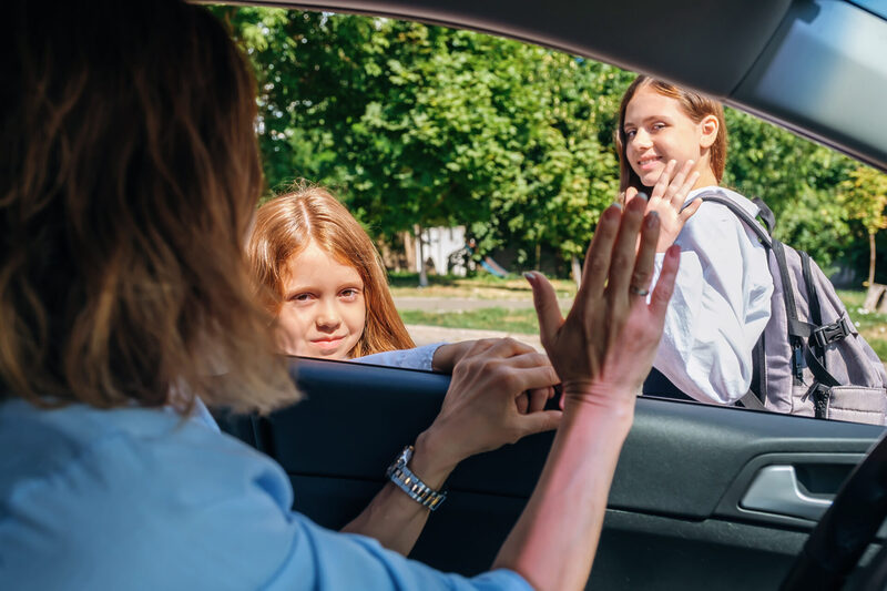 Mother,Sitting,Inside,The,Car,And,Gesturing,With,Hand,Goodbye | Warrantywise Mother waving children off at school