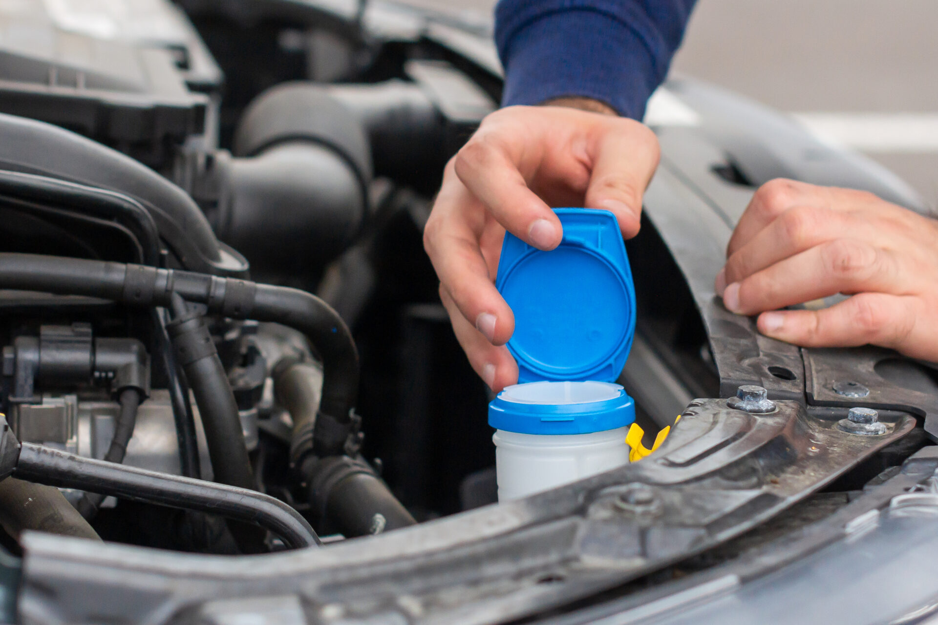 Closeup mans hands checking a level of a glass washer Car repairing concept Automobile service | Warrantywise