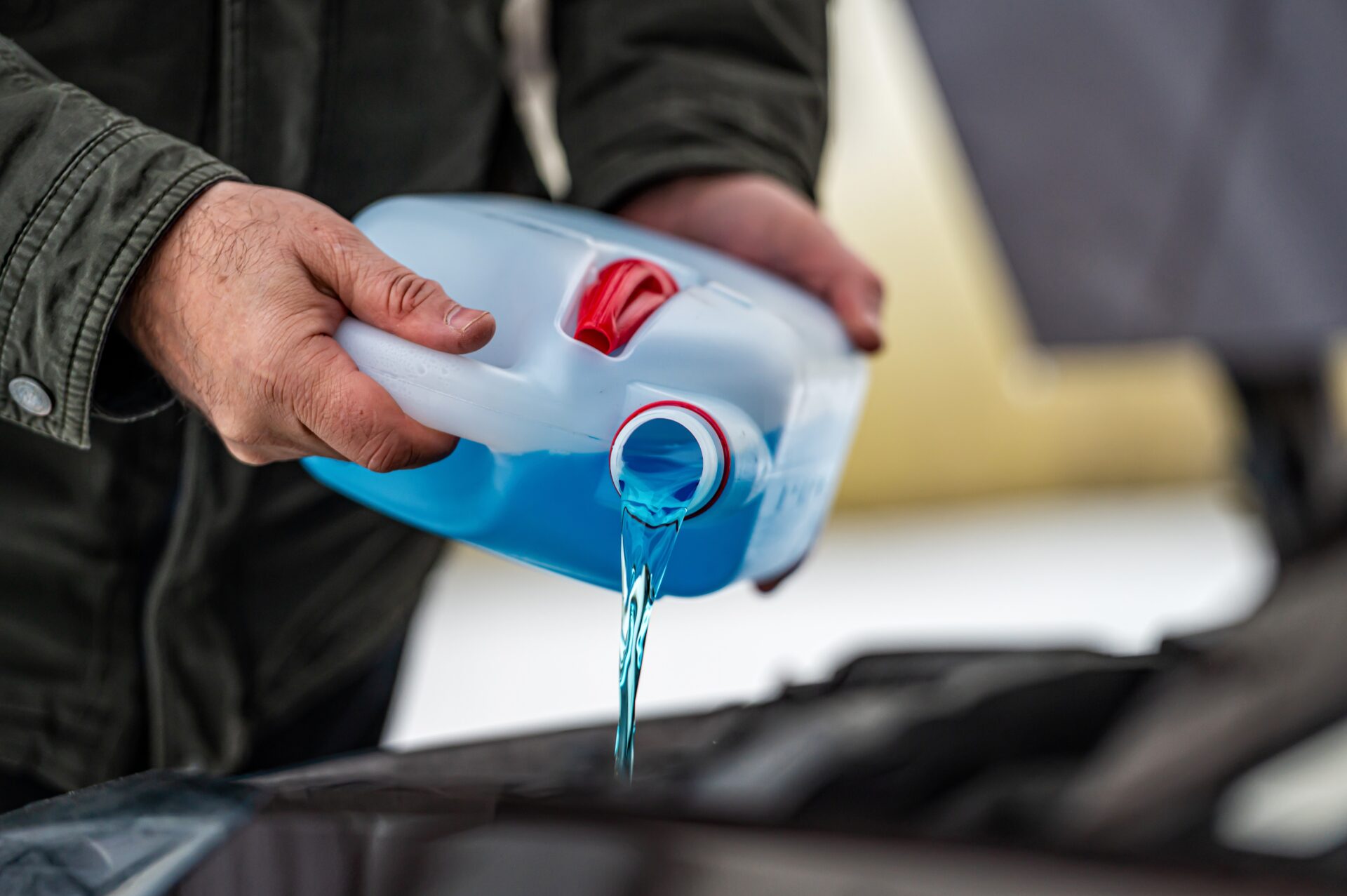 driver refilling the blue non-freezing windshield washer liquid | Warrantywise
