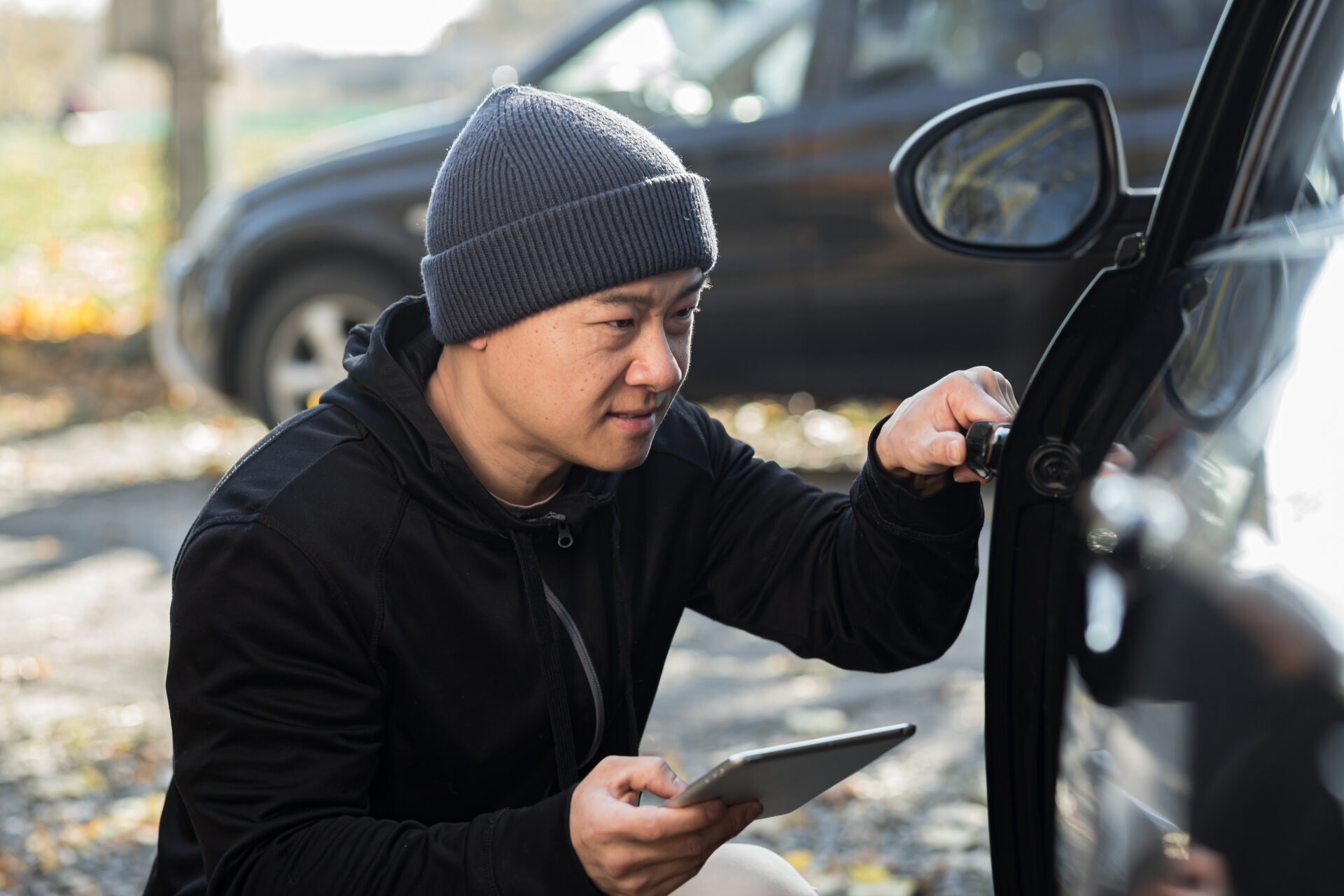 male bandit thief car thief asian uses a tablet to turn off the car alarm | Warrantywise