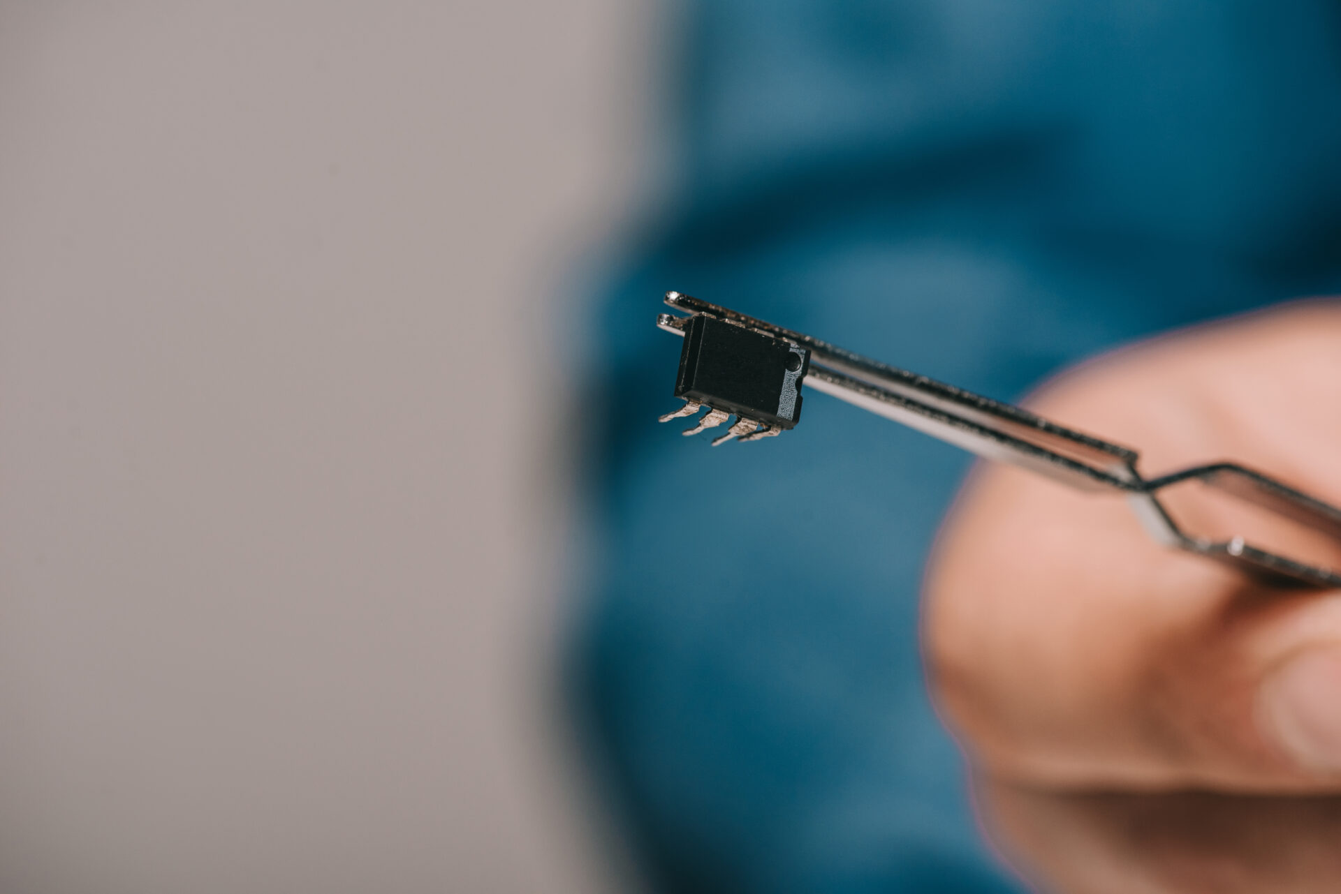 selective focus of tweezers with microchip in hand of scientist | Warrantywise