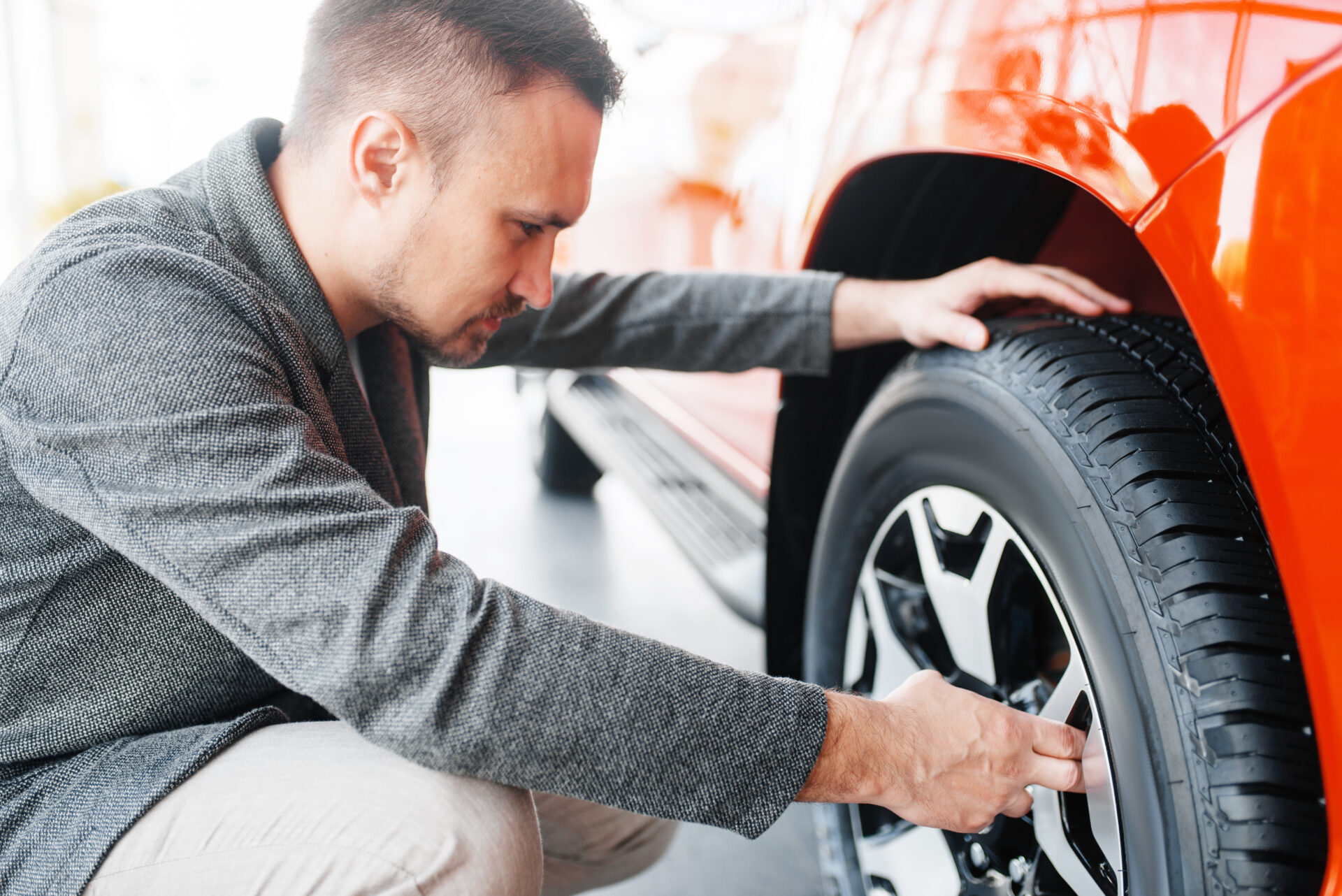 Man looks on wheels of new car in showroom | Warrantywise