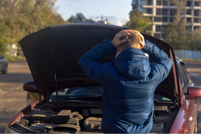 COVER_IMG | Warrantywise Man standing by the roadside with the bonnet of his car open, holding his head in frustration while looking into the engine bay
