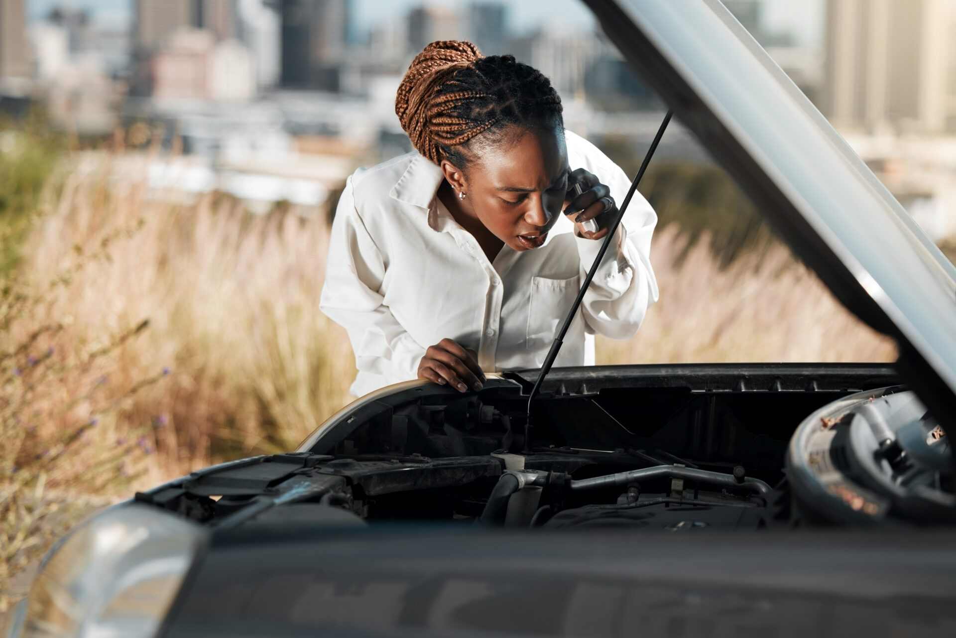 phone-call-stress-and-black-woman-fixing-car-in-t-2026-01-09-09-37-39-utc | Warrantywise black woman on mobile phone while looking at car engine