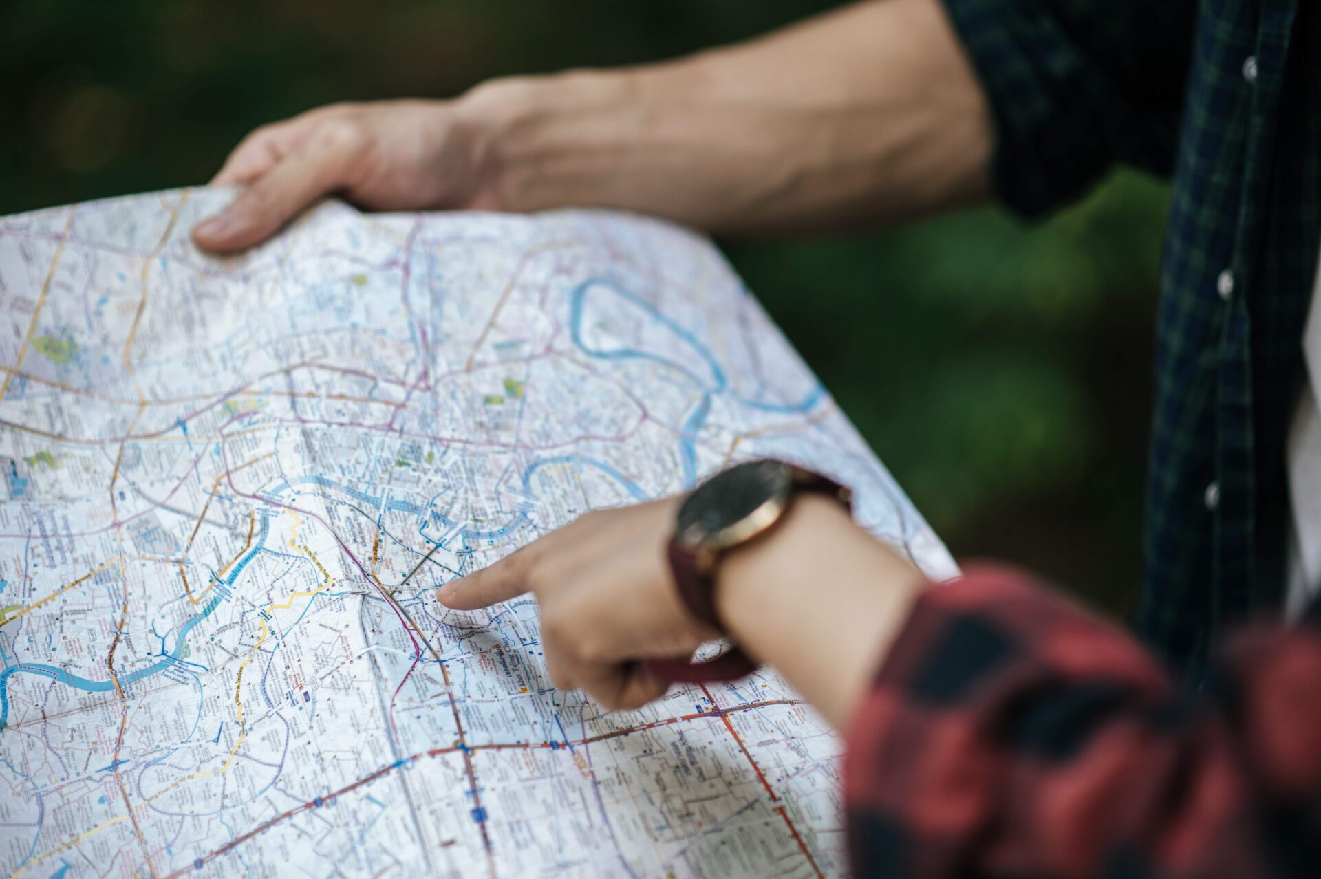 Young trekking couple use map while walking on forest trail | Warrantywise hand pointing to position on road map