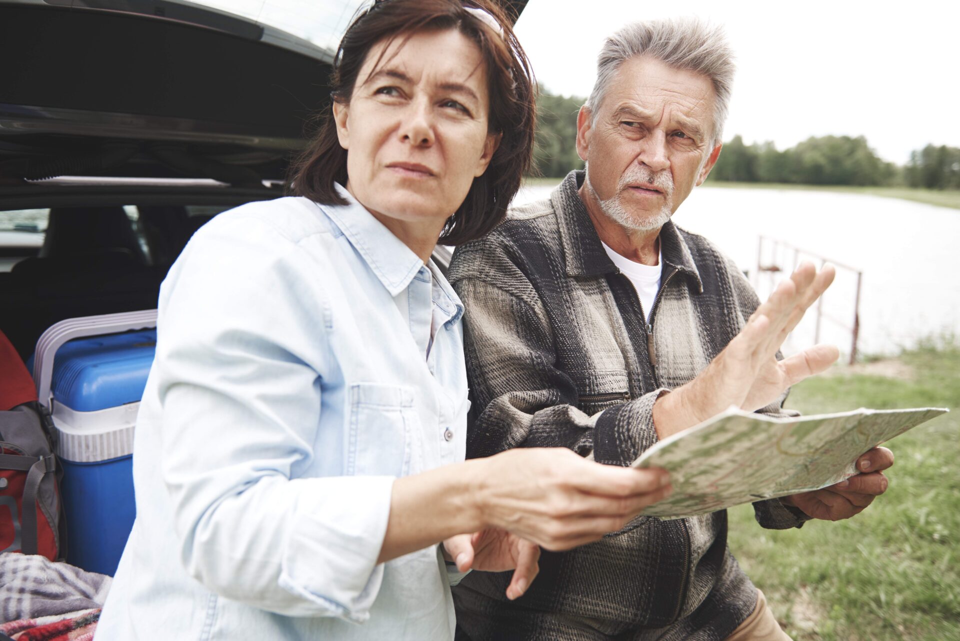 Mature couple in rural setting standing beside car looking at map | Warrantywise middle aged couple looking at road map